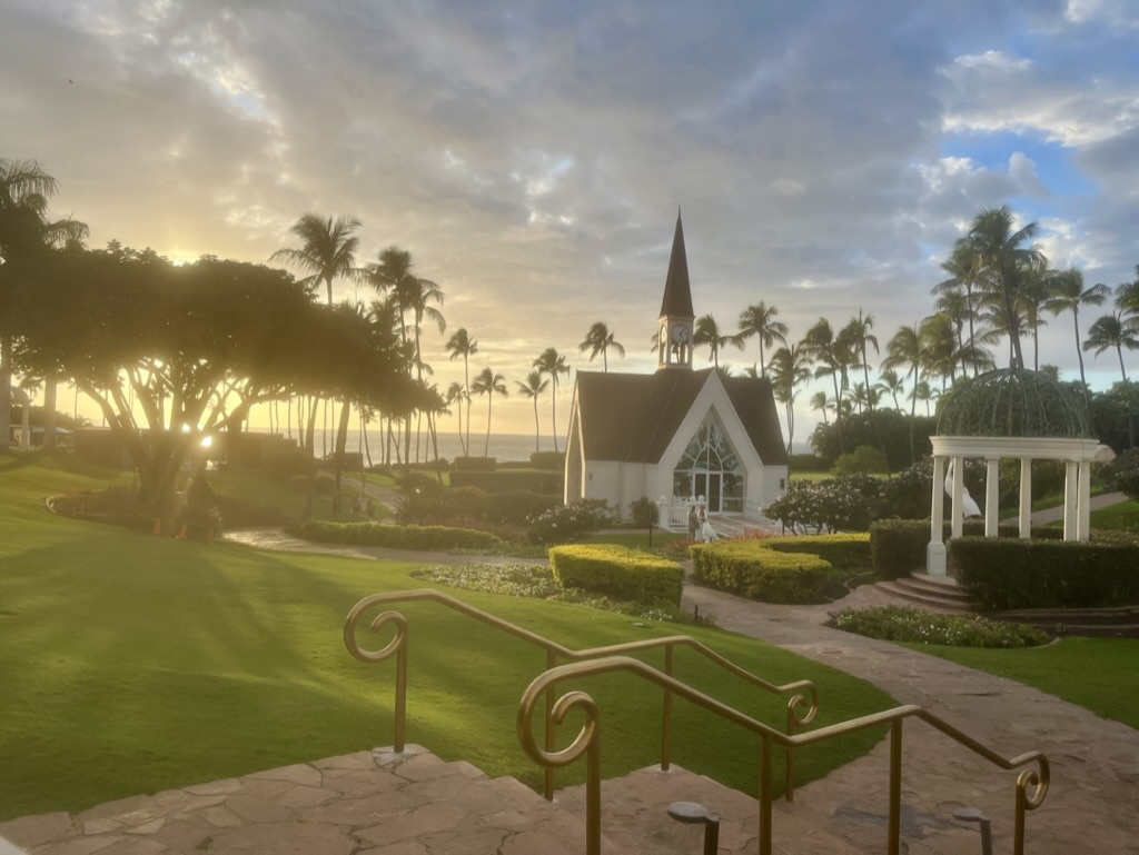 A white chapel framed by palms at sunset