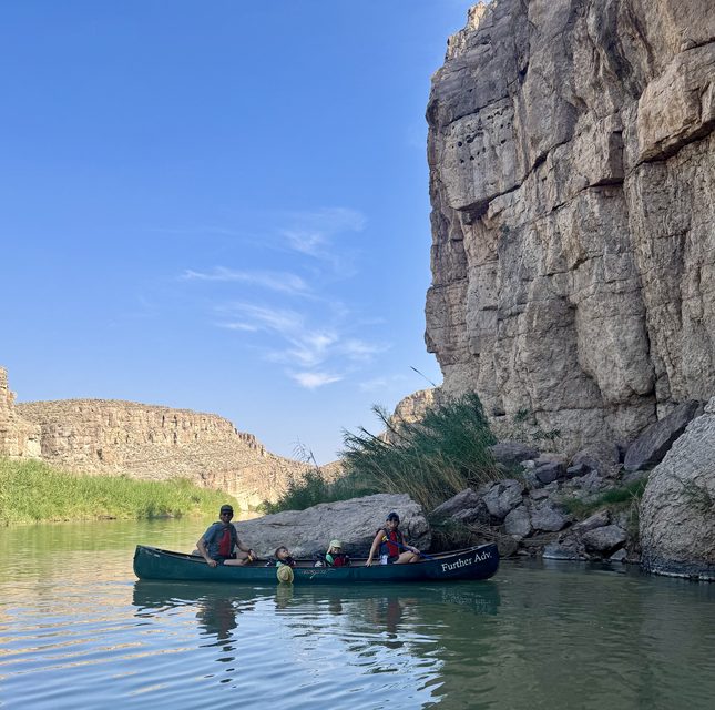 A canoe trip on a river beneath tall canyon cliffs